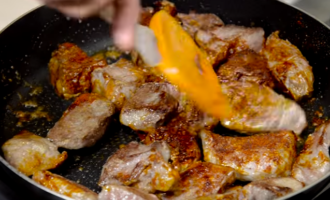 Посыпать жареное мясо сушеным перцем и еще немного обжарить.