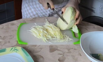 Удалите с капусты верхние листья, затем промойте. Капусту нарезать тонкой соломкой. Если в вашем арсенале есть специальная терка, воспользуйтесь ею.