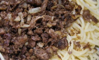 Переносим макароны на сковороду и обжариваем вместе с мясом и луком пять минут. 